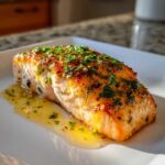 A perfectly cooked fillet of Garlic Butter Salmon with Lemon Sauce, glistening with butter and topped with fresh parsley.