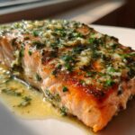 Close-up of a perfectly cooked fillet of Garlic Butter Salmon with Lemon Garlic Sauce, topped with herbs.