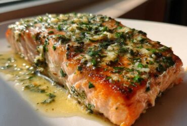 Close-up of a perfectly cooked fillet of Garlic Butter Salmon with Lemon Garlic Sauce, topped with herbs.
