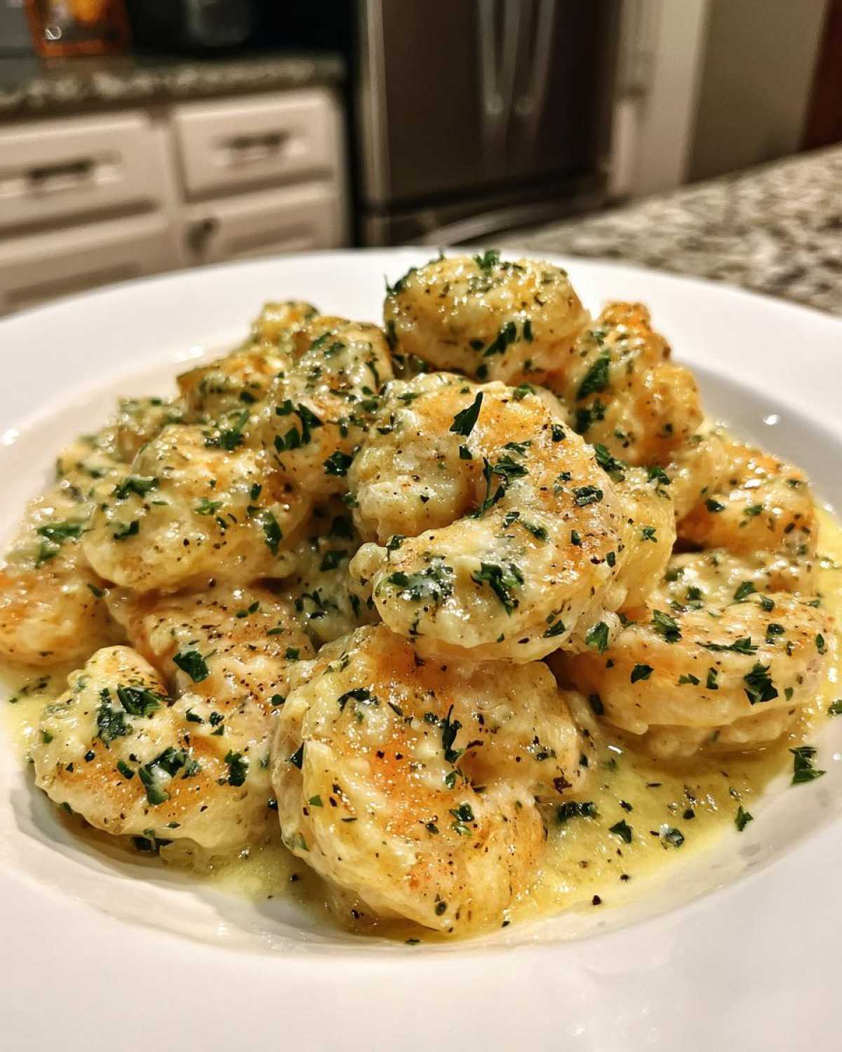 Plump shrimp coated in a rich, creamy Parmesan sauce and sprinkled with fresh parsley, ready to eat.