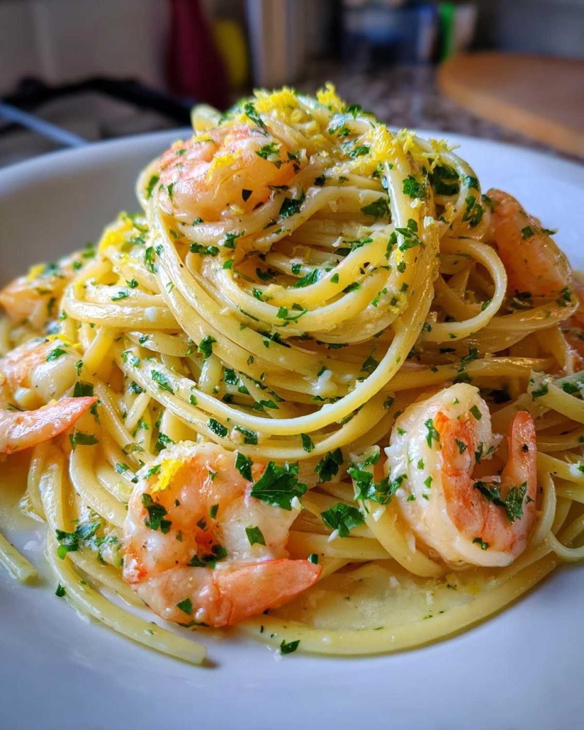 A close-up of a serving of Garlic Butter Shrimp Pasta with Lemon Flavor, topped with fresh parsley and bright yellow lemon zest.