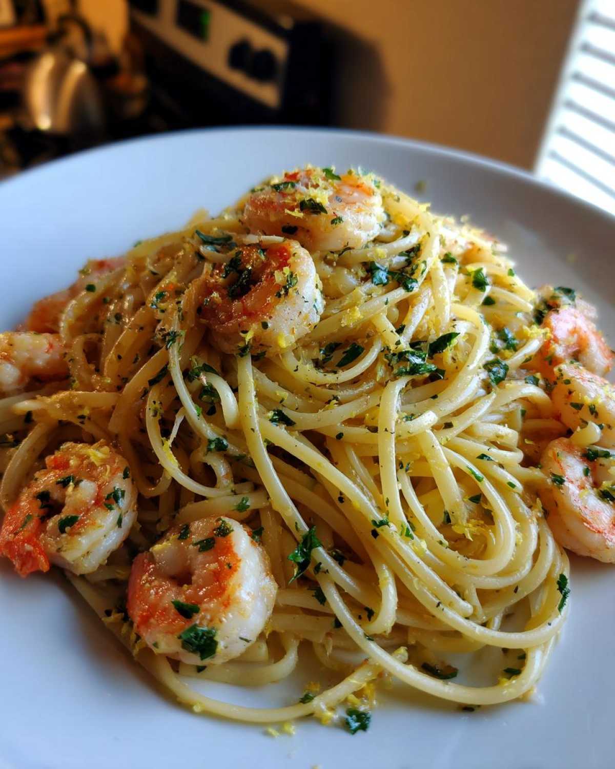 A close-up of a plate piled high with Garlic Butter Shrimp Pasta with Lemon Flavor, topped with shrimp and herbs.