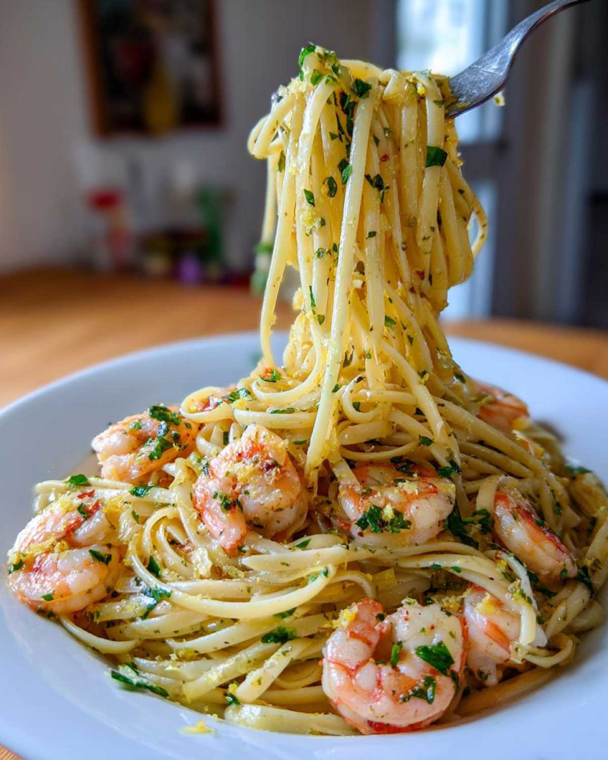 A fork lifts a swirl of linguine from a plate of Garlic Butter Shrimp Pasta with Lemon Flavor, garnished with parsley.