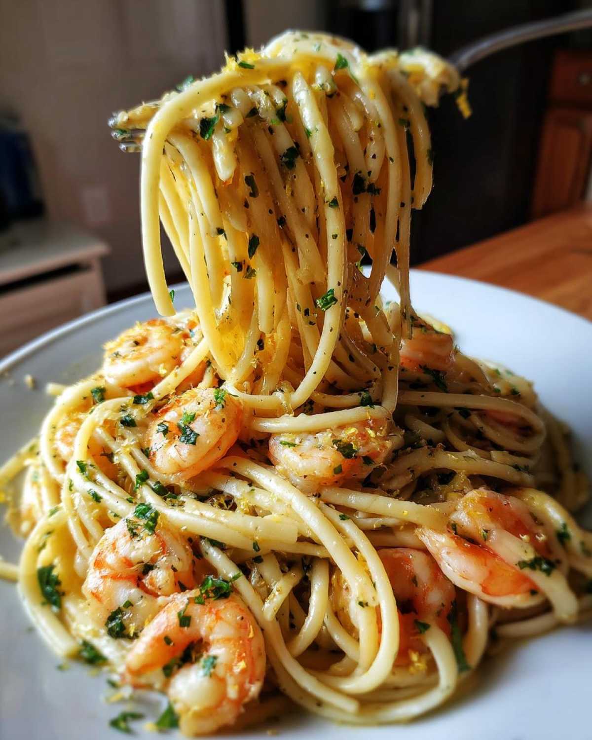 A fork lifts a generous portion of Garlic Butter Shrimp Pasta with Lemon Flavor, showing coated spaghetti, pink shrimp, and lemon zest.