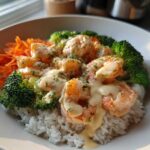 Close-up of a Garlic Butter Shrimp Rice Bowl topped with creamy garlic sauce, broccoli, and shredded carrots.