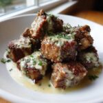 Close-up of seared Garlic Butter Steak Bites drizzled with creamy garlic sauce and fresh parsley.