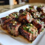 Close-up of seared Garlic Butter Steak Bites with a juicy center, topped with minced garlic and parsley.