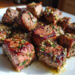 Close-up of perfectly cooked Garlic Butter Steak Bites, glistening with garlic, butter, and herbs, showing a juicy center.