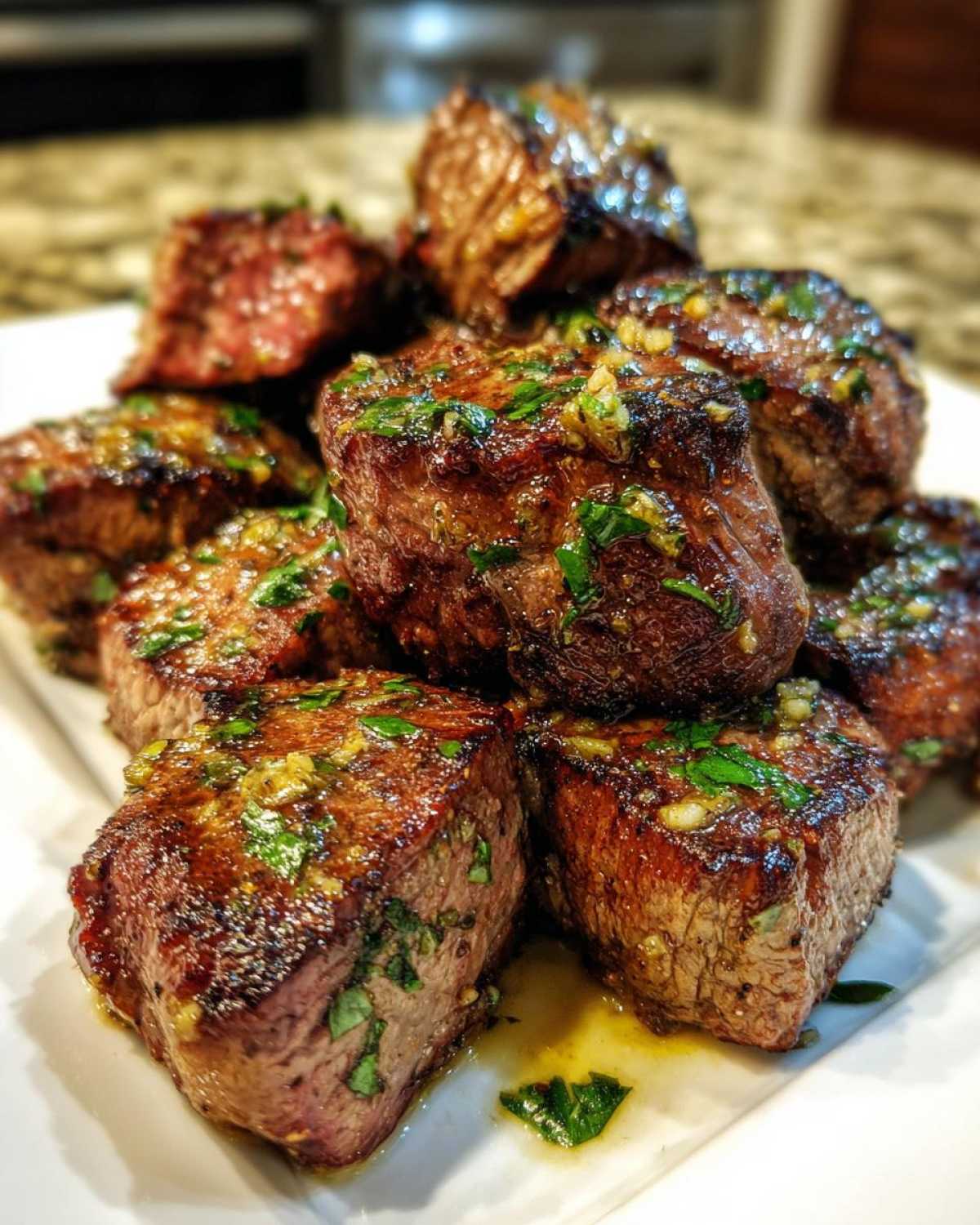 A close-up of seared Garlic Butter Steak Bites with a juicy center, glistening with garlic butter and parsley.