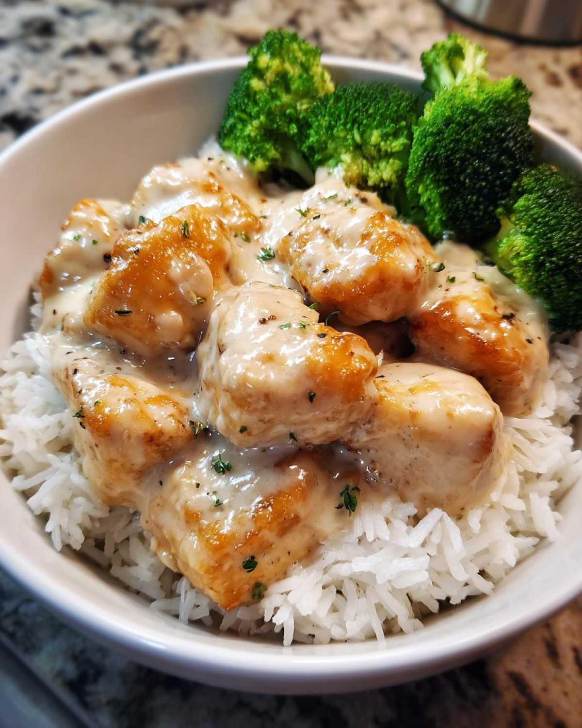 Close-up of Honey Garlic Chicken Bowl with creamy sauce served over white rice and steamed broccoli florets.