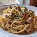 A close-up of creamy Honey Garlic Chicken Pasta featuring fettuccine noodles, chunks of chicken, and a light garnish of parsley.