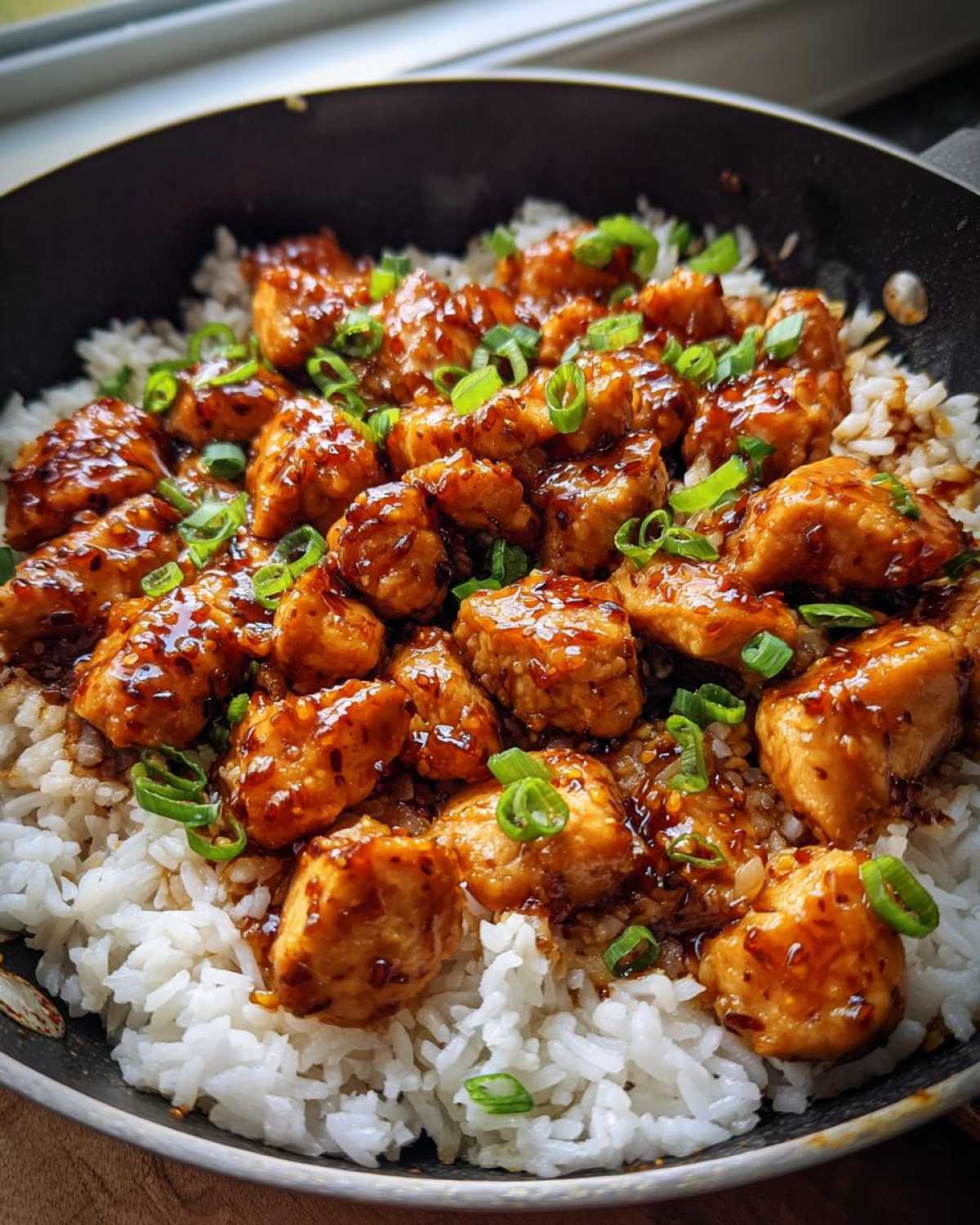 Close-up of glistening Honey Garlic Chicken Skillet with Rice, topped with fresh green onions.