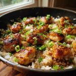 Close-up of glazed Honey Garlic Chicken Skillet with Rice topped with fresh green onions.