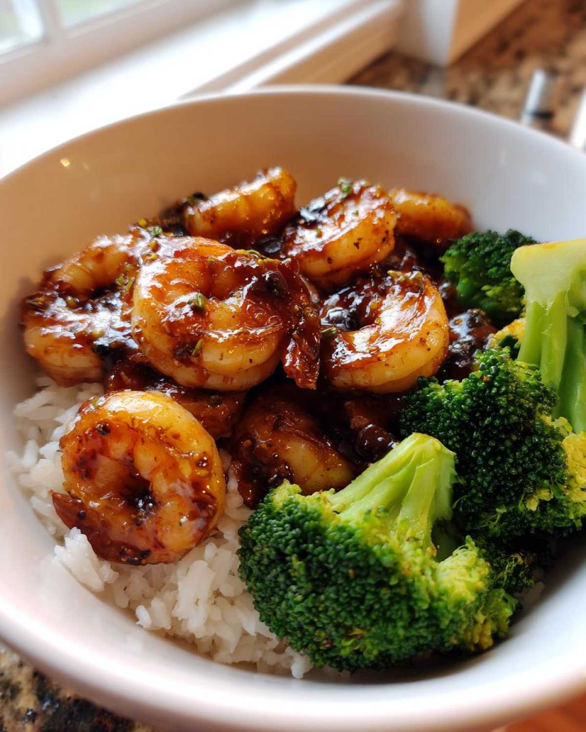 Close-up of a Honey Garlic Shrimp Bowl Quick Dinner featuring glazed shrimp, white rice, and bright green broccoli florets.