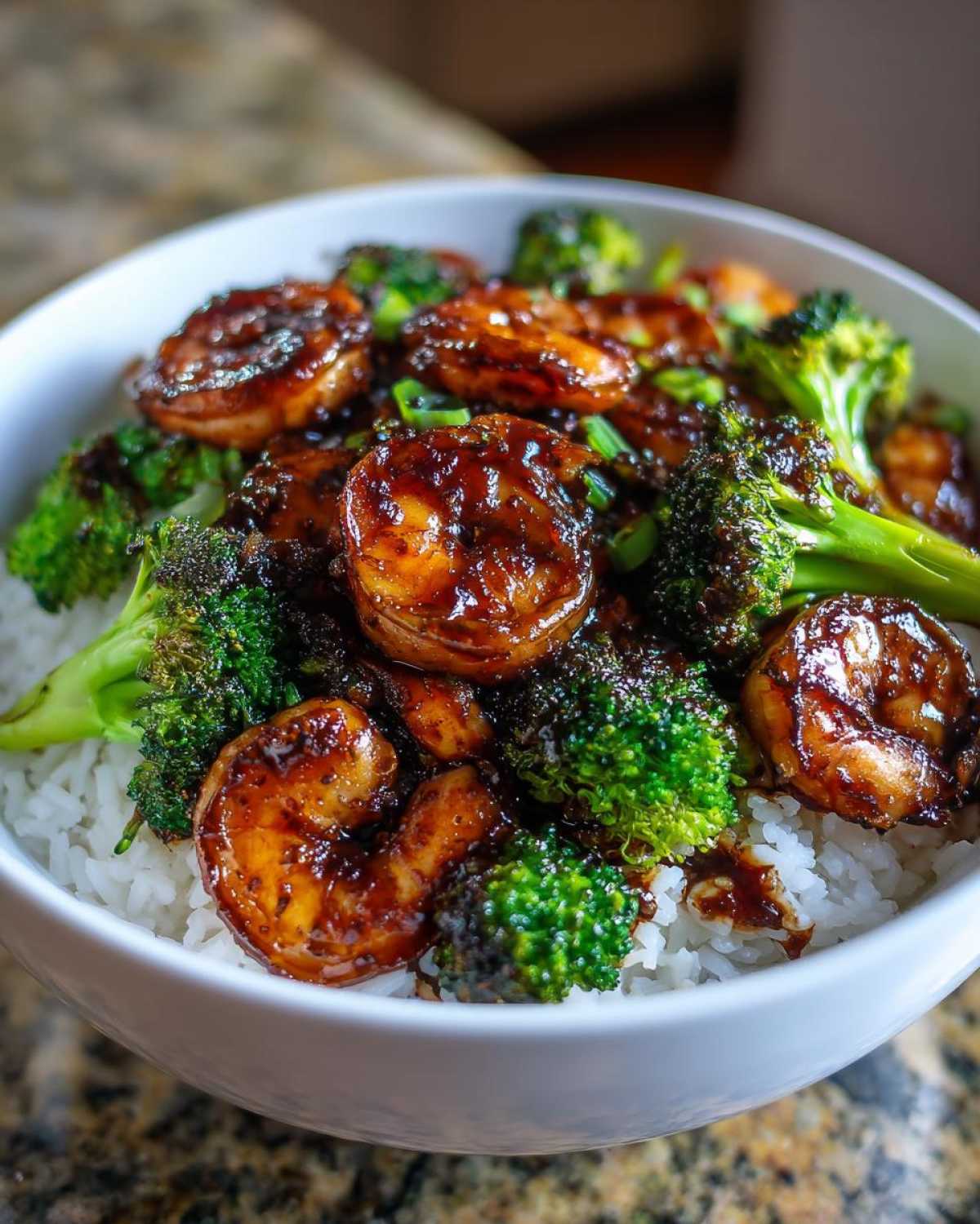 Close-up of a Honey Garlic Shrimp Bowl with glossy, glazed shrimp and bright green broccoli florets over white rice.