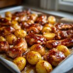 Close-up of glistening Honey Mustard Chicken Bake with Potatoes baked together on a sheet pan.
