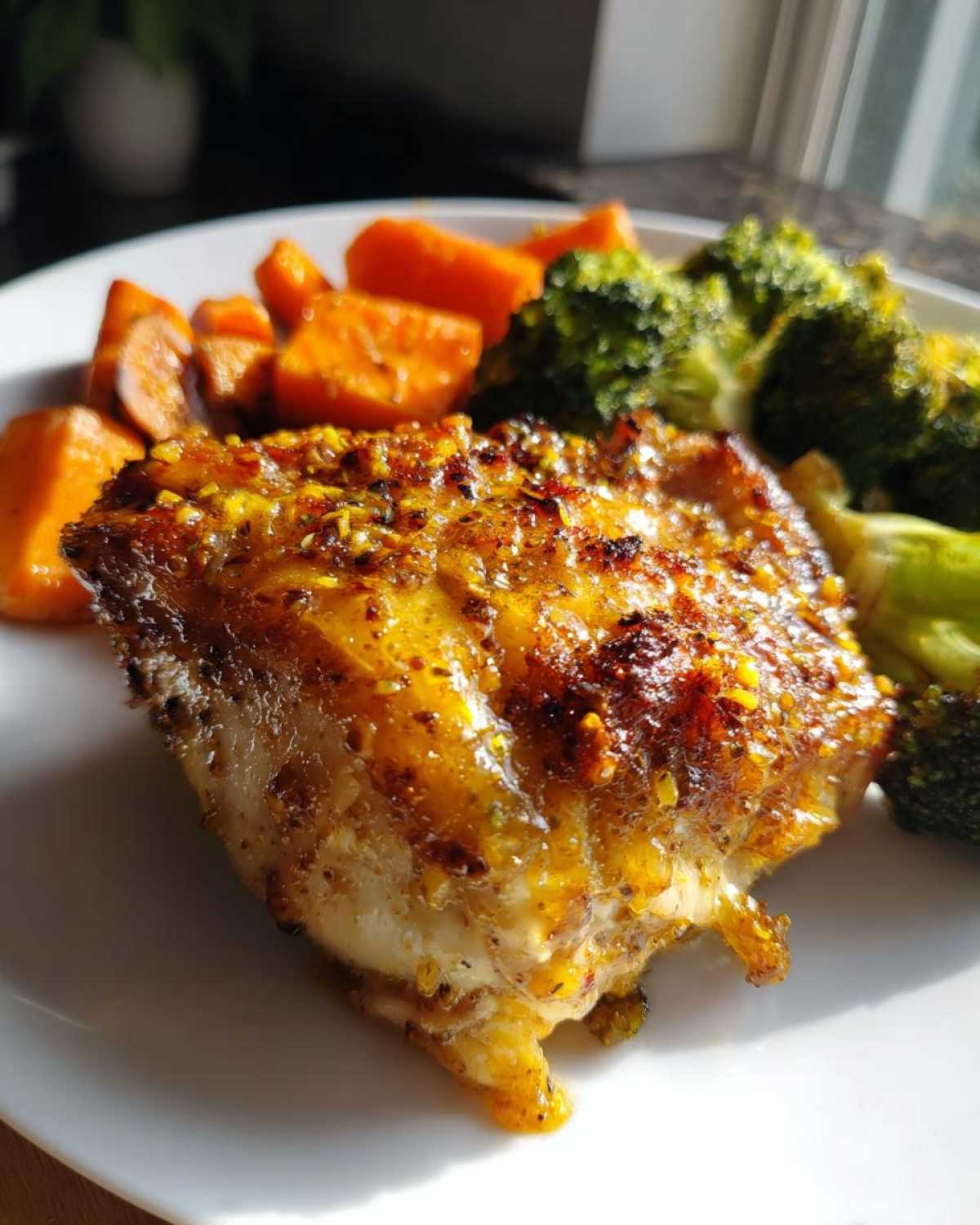 Close-up of a Honey Mustard Chicken Bake with a golden glaze, served alongside roasted sweet potatoes and broccoli.