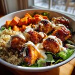 Close-up of a Honey Mustard Chicken Bowl with creamy sauce drizzled over crispy chicken, quinoa, and roasted sweet potatoes.