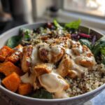 Close-up of a Honey Mustard Chicken Bowl with creamy sauce drizzled over seasoned chicken, sweet potatoes, and quinoa.