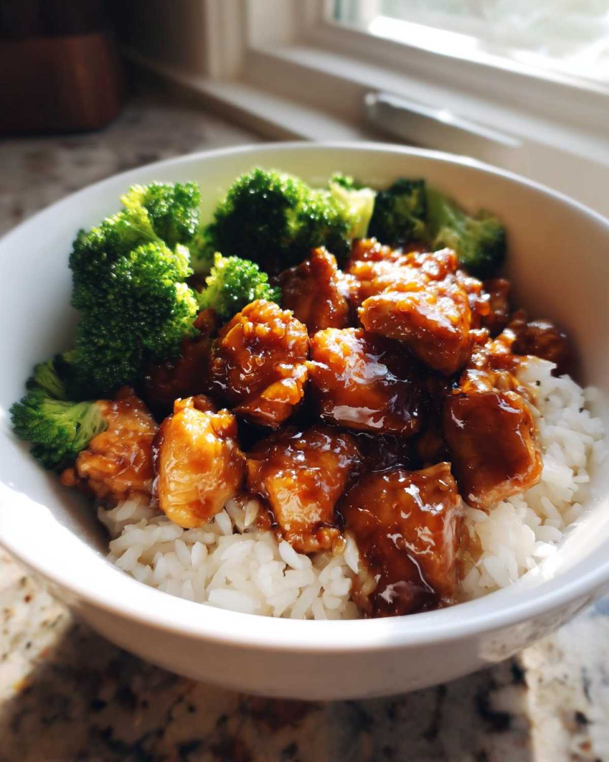 A close-up of a Honey Soy Chicken Bowl Quick Dinner Idea featuring glazed chicken pieces over white rice and bright green steamed broccoli.