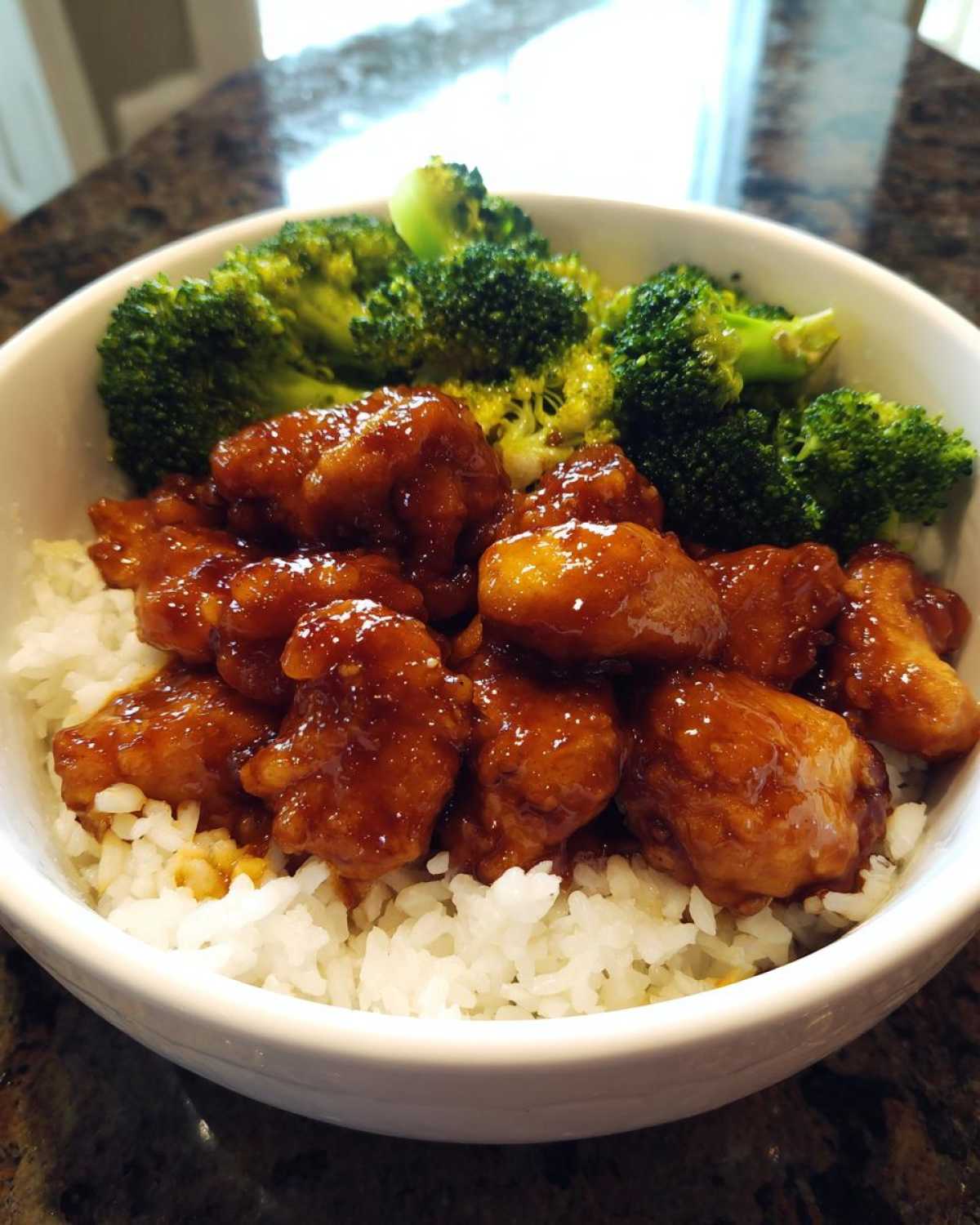 A close-up of a Honey Soy Chicken Bowl Quick Dinner Idea featuring glazed chicken pieces over white rice with steamed broccoli.