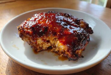 Close-up of a perfectly cooked Honey Soy Chicken Thighs with crispy, dark edges and a thick, shiny glaze.