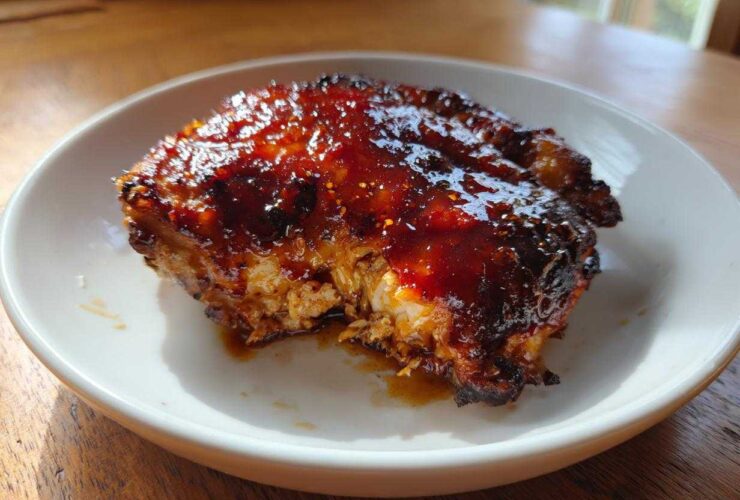 Close-up of a perfectly cooked Honey Soy Chicken Thighs with crispy, dark edges and a thick, shiny glaze.