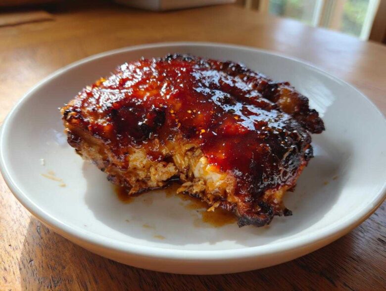 Close-up of a perfectly cooked Honey Soy Chicken Thighs with crispy, dark edges and a thick, shiny glaze.