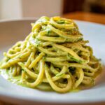 A close-up of pasta coated in creamy Italian Zucchini Sauce, served on a white plate.