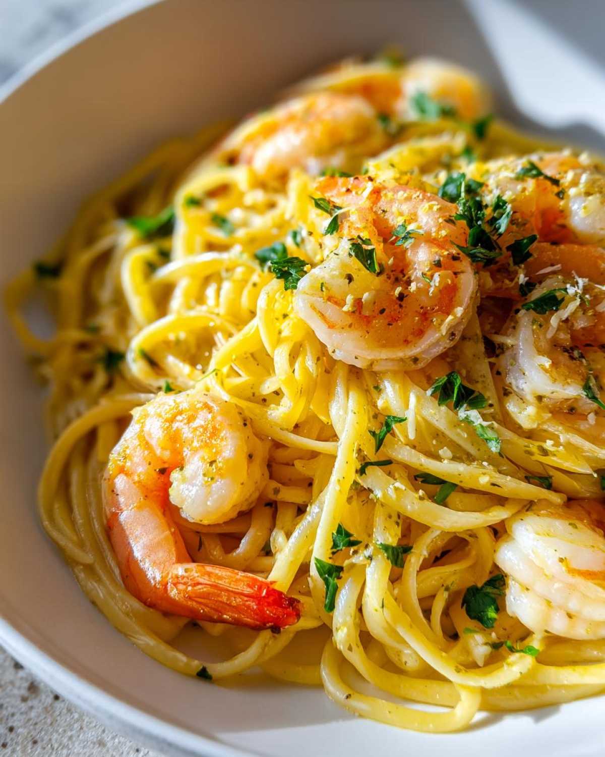 Close-up of a bowl of Lemon Butter Shrimp Pasta Ready in 20 Minutes, topped with cooked shrimp and fresh parsley.