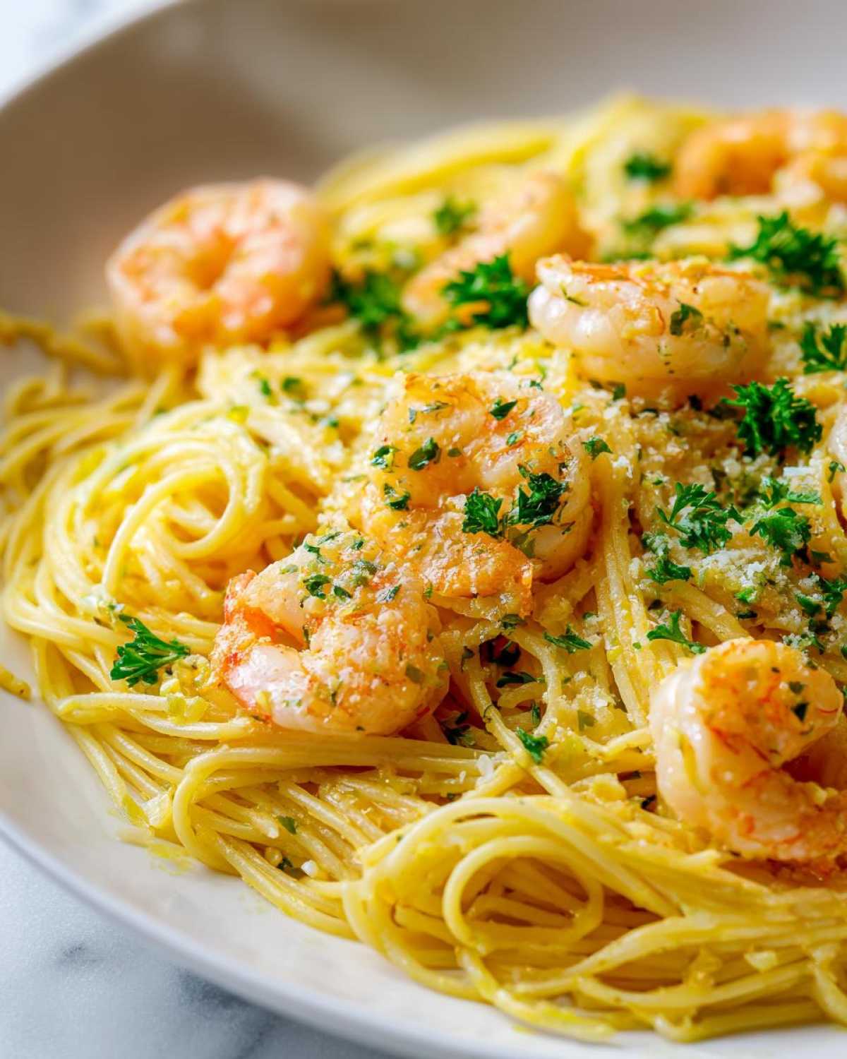 A close-up of bright Lemon Butter Shrimp Pasta tossed in a light sauce, topped with sautéed shrimp and fresh parsley.