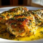 Two golden-brown chicken breasts covered in a rich lemon garlic butter sauce and fresh parsley, ready to eat.