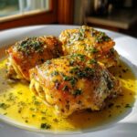 Three pieces of golden brown Lemon Garlic Butter Chicken Easy Skillet resting in a pool of bright yellow butter sauce and topped with parsley.