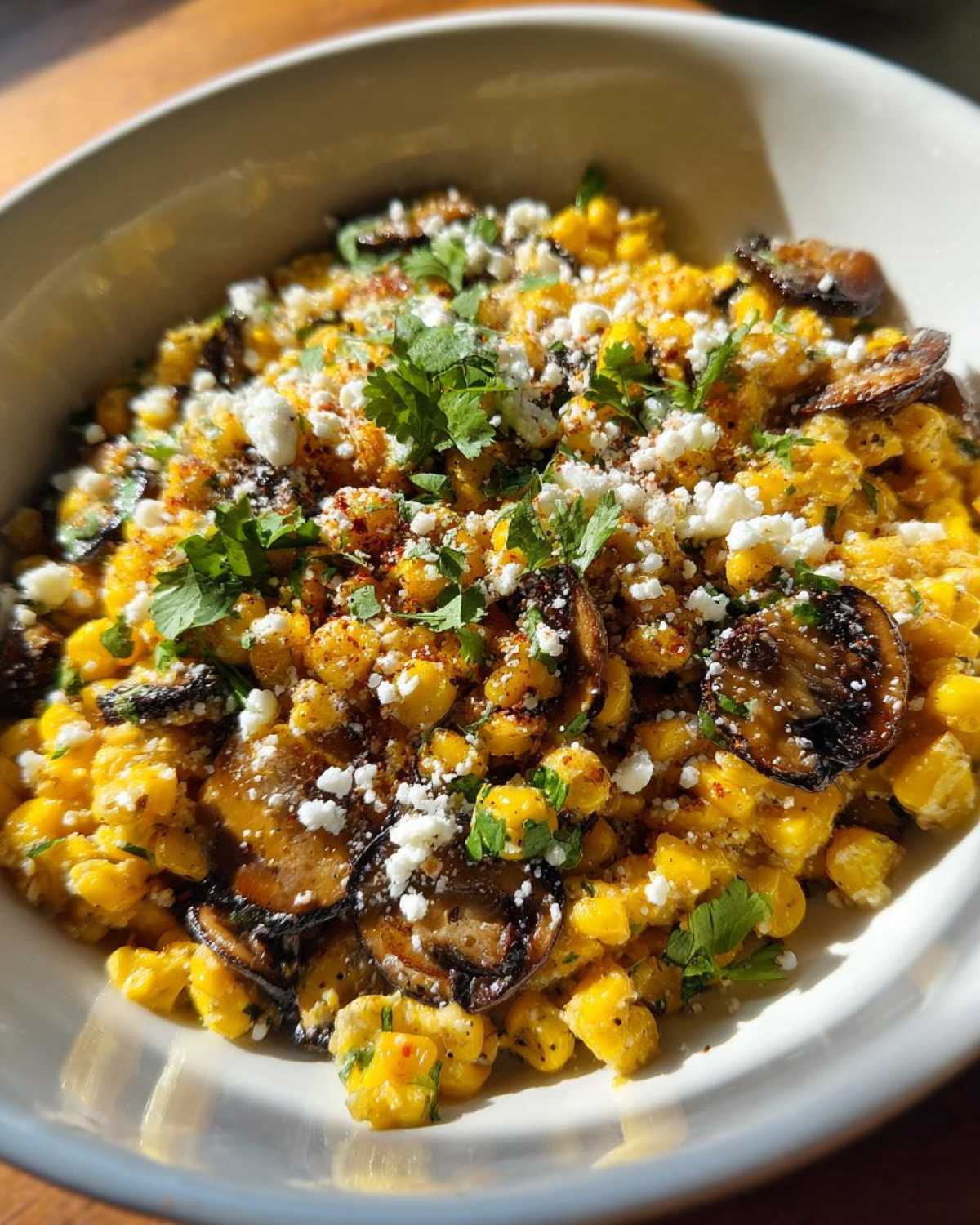 A close-up bowl of vibrant Mexican Street Corn Salad MushroomSalus, topped with cotija cheese and cilantro.