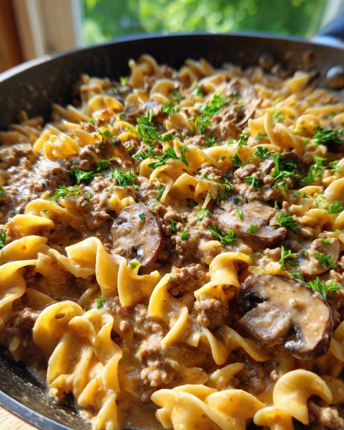 Close-up of creamy One Pan Ground Beef Stroganoff with egg noodles, mushrooms, and parsley garnish.