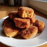 A stack of freshly made Soft & Sweet Cinnamon Sugar Biscuit Bites piled high on a white plate, glistening with sugar.