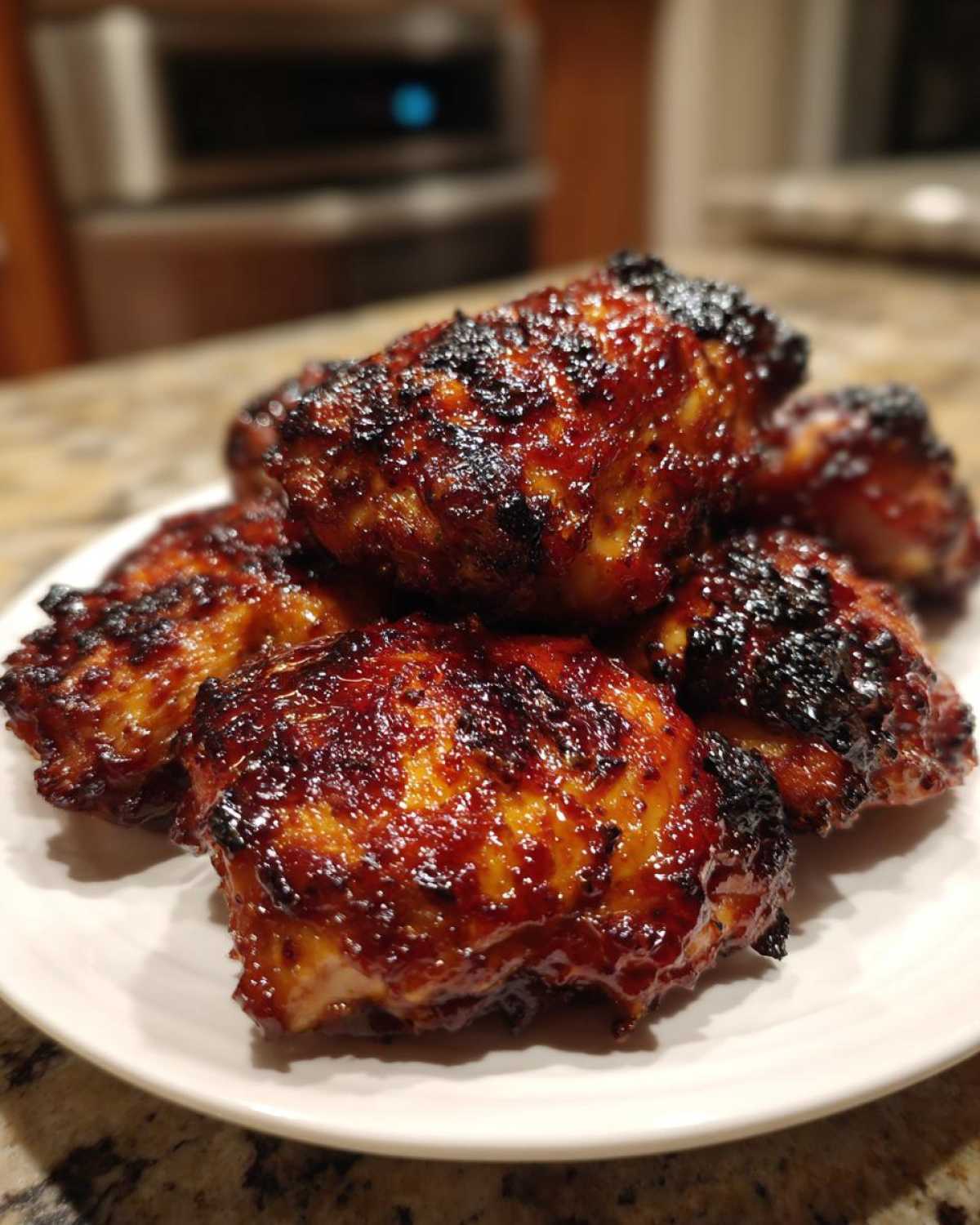 Close-up of several perfectly cooked Sticky BBQ Chicken Thighs with Honey Glaze, featuring a dark, caramelized, and shiny exterior.