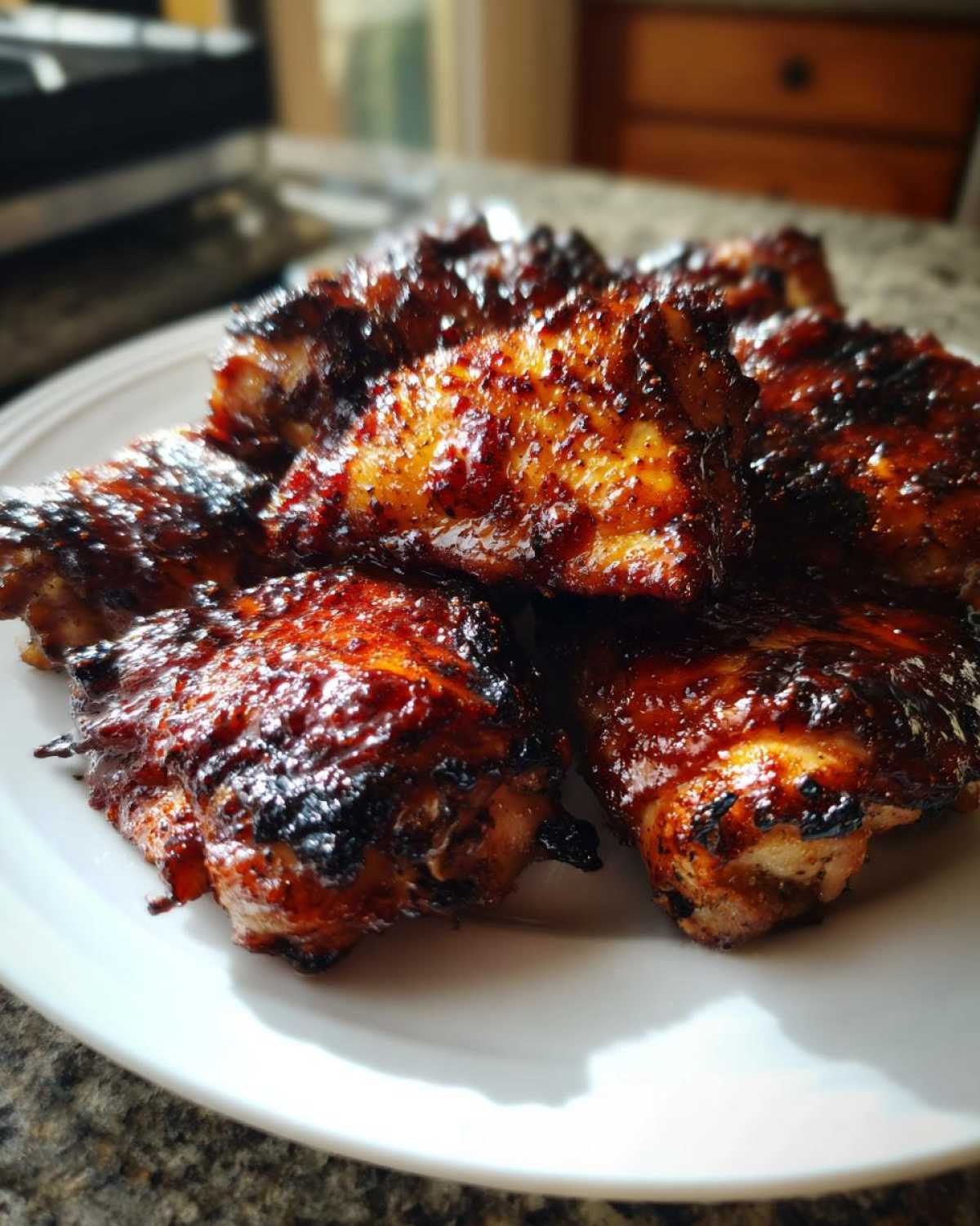Close-up of several Sticky BBQ Chicken Thighs with Honey Glaze, featuring a dark, caramelized, and shiny exterior.