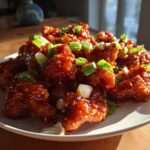 Close-up of Sticky Sweet Chili Chicken Easy Recipe pieces glistening with sauce and topped with chopped green onions.