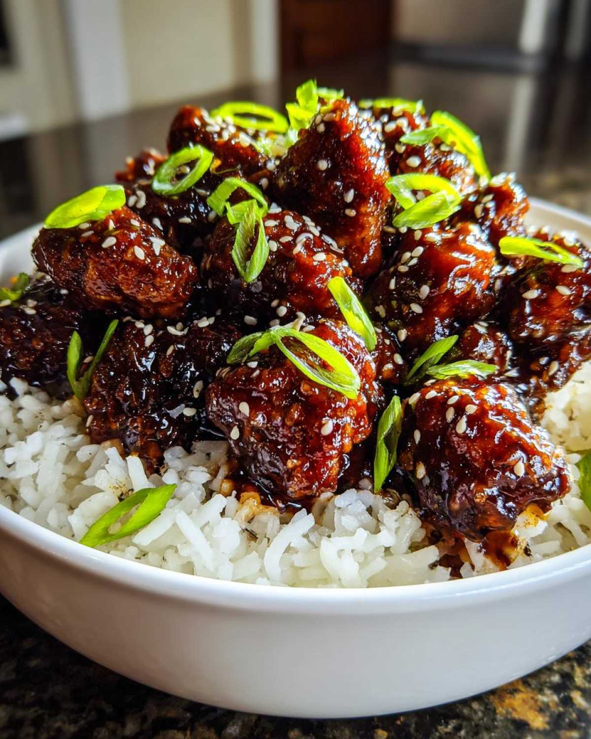 Close-up of Sticky Sweet Chili Chicken Skillet pieces coated in glaze, served over white rice and topped with sesame seeds and green onions.