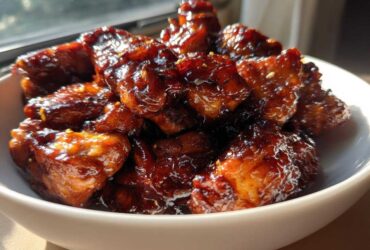 Close-up of glossy, dark brown Sticky Teriyaki Chicken Easy Weeknight Meal pieces piled high in a white bowl.