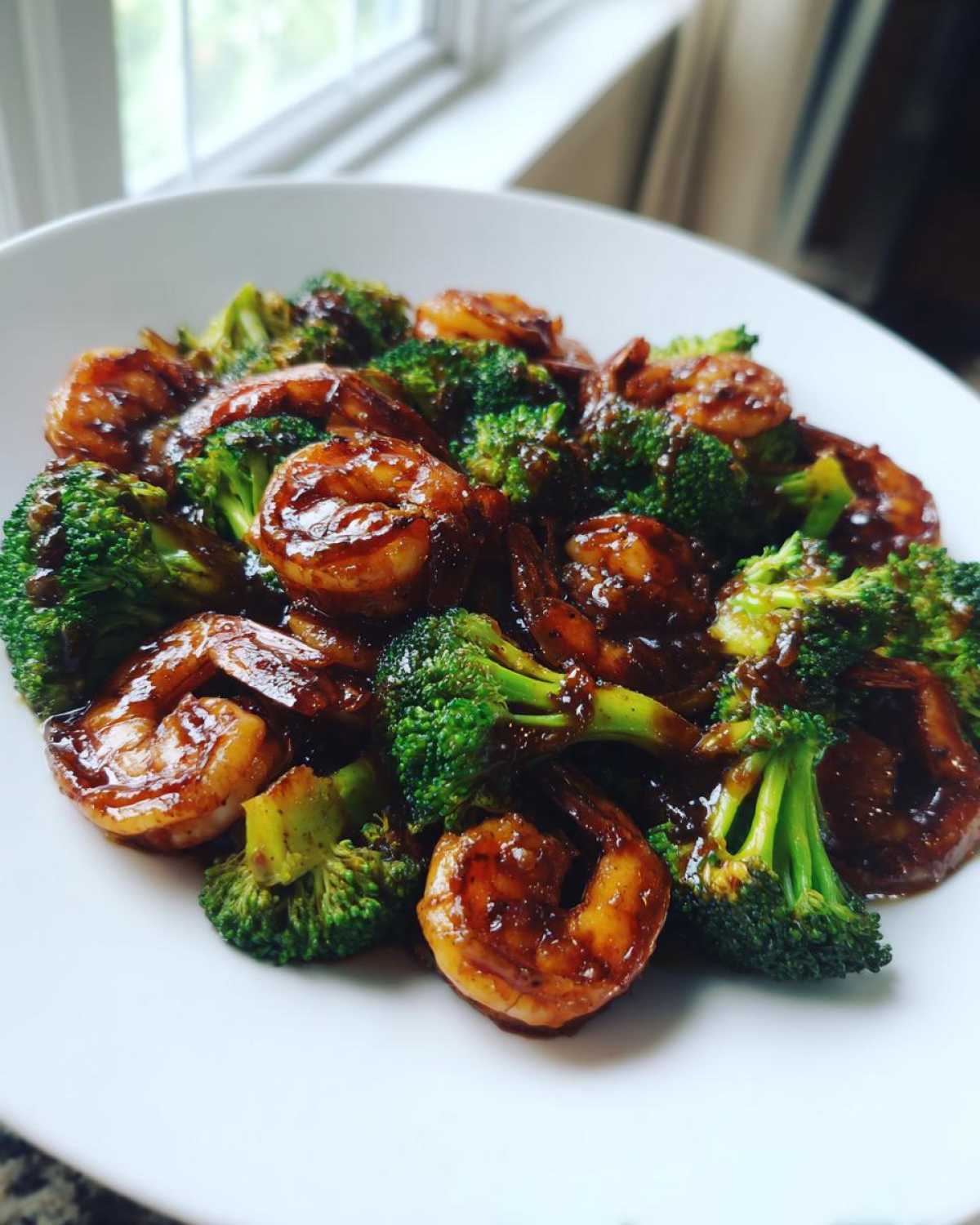 Close-up of Sticky Teriyaki Shrimp Stir Fry Quick Meal featuring plump shrimp coated in dark sauce alongside bright green broccoli florets.