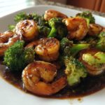 Close-up of succulent shrimp coated in a dark, sticky teriyaki sauce with bright green broccoli florets.