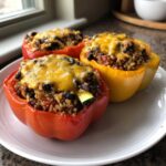 Three colorful Vegetarian Stuffed Bell Peppers Easy Dinner halves filled with rice, black beans, and topped with melted cheddar cheese.
