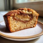Close-up of a moist slice of Apple Cinnamon Loaf showing a swirl of cinnamon filling and a baked apple piece.