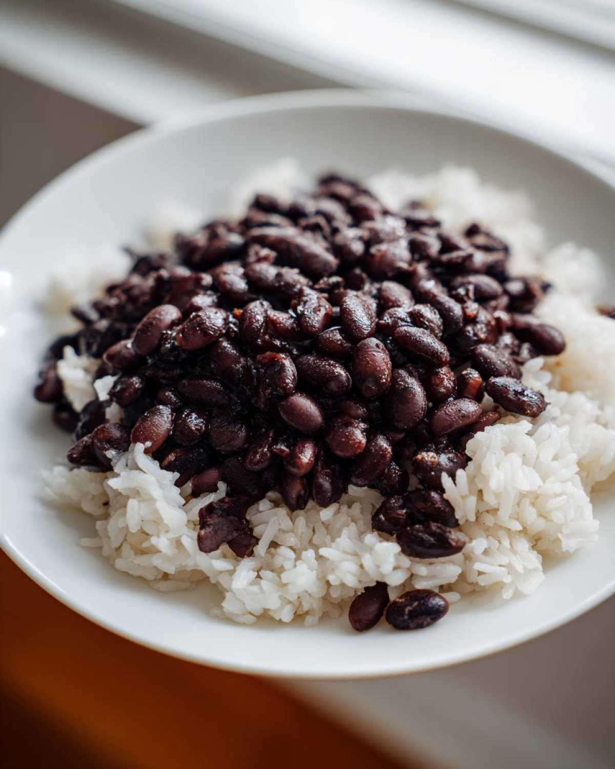 Close-up of a white bowl filled with fluffy white rice topped generously with seasoned black beans and rice.