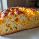 Cross-section of a slice of golden-brown Cheese Bread Quick Bread 30 Minutes showing fluffy interior and melted cheddar cheese.