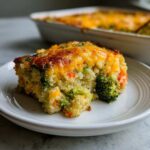 A serving of Cheesy Veggie Quinoa Casserole with visible broccoli florets and a melted cheddar cheese top.