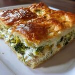 A close-up of a square slice of Chicken Crescent Roll Casserole showing a golden crust and creamy broccoli filling.