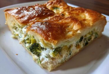 A close-up of a square slice of Chicken Crescent Roll Casserole showing a golden crust and creamy broccoli filling.